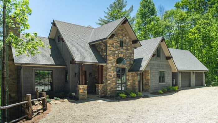 Custom hybrid timber frame home with natural stone accents in a scenic mountain setting.