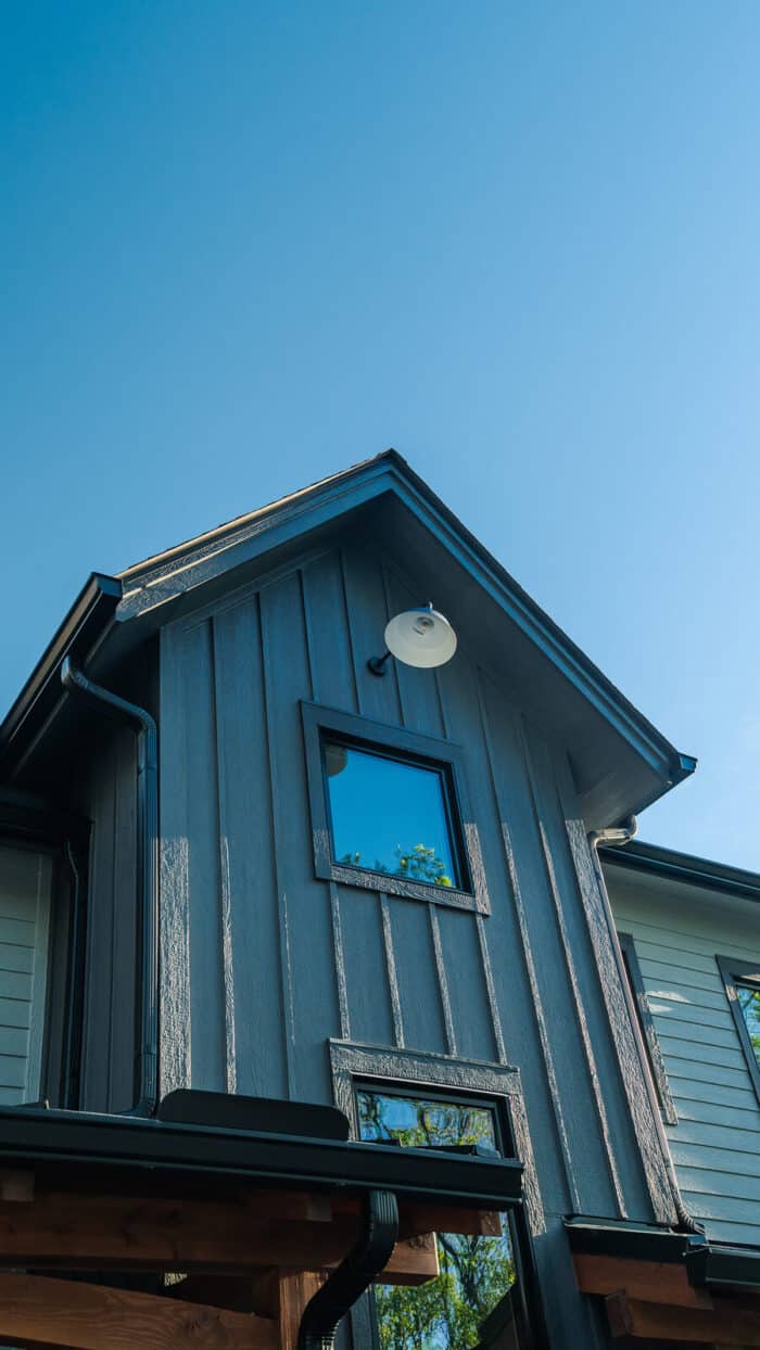 Elegant modern log home with natural wood siding set against a clear blue sky, showcasing craftsmans.