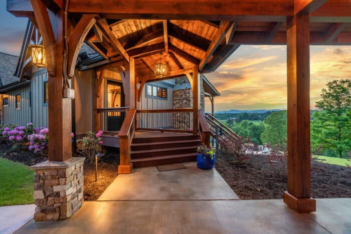 Elegant natural log cabin with timber frame accents set in a scenic mountain landscape at sunset.