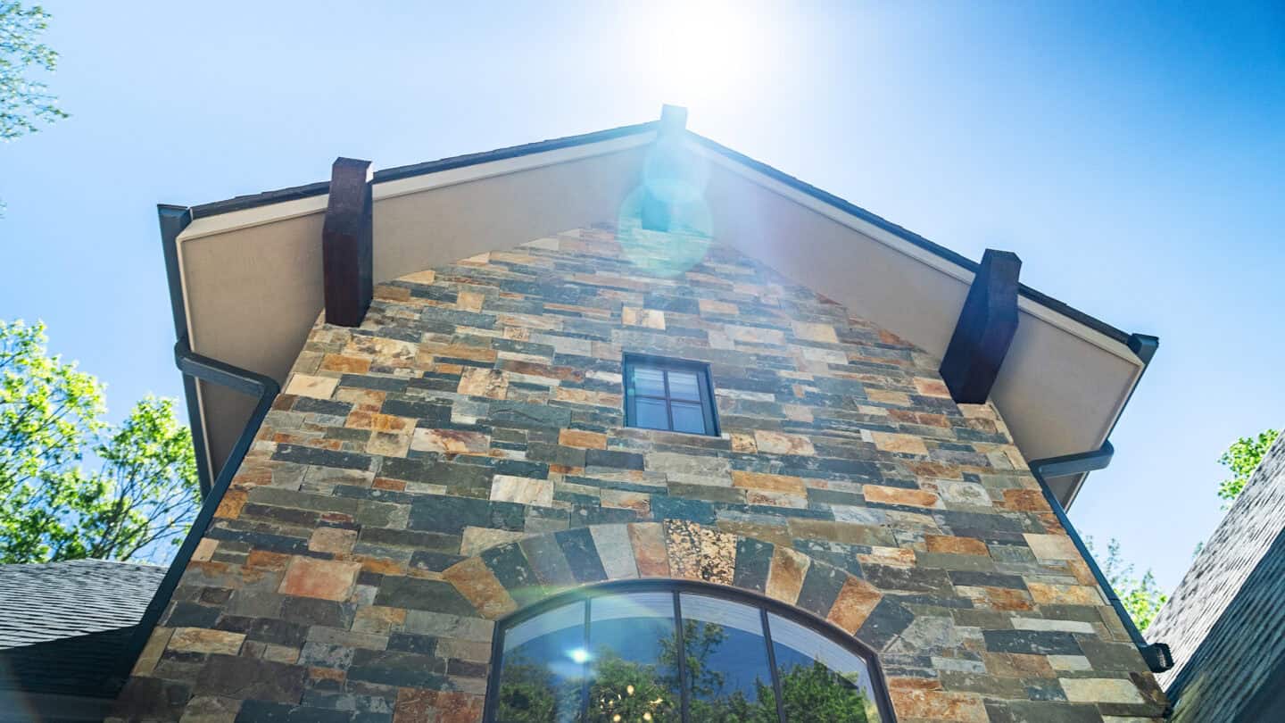 Custom log cabin with natural stone exterior in a mountain setting, eco-friendly timber frame design.
