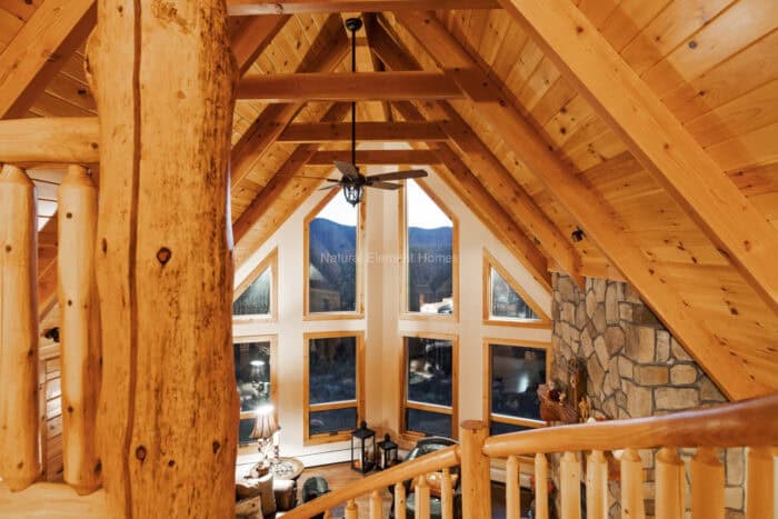 Custom log cabin with timber frame architecture in a mountain setting, crafted from natural material.