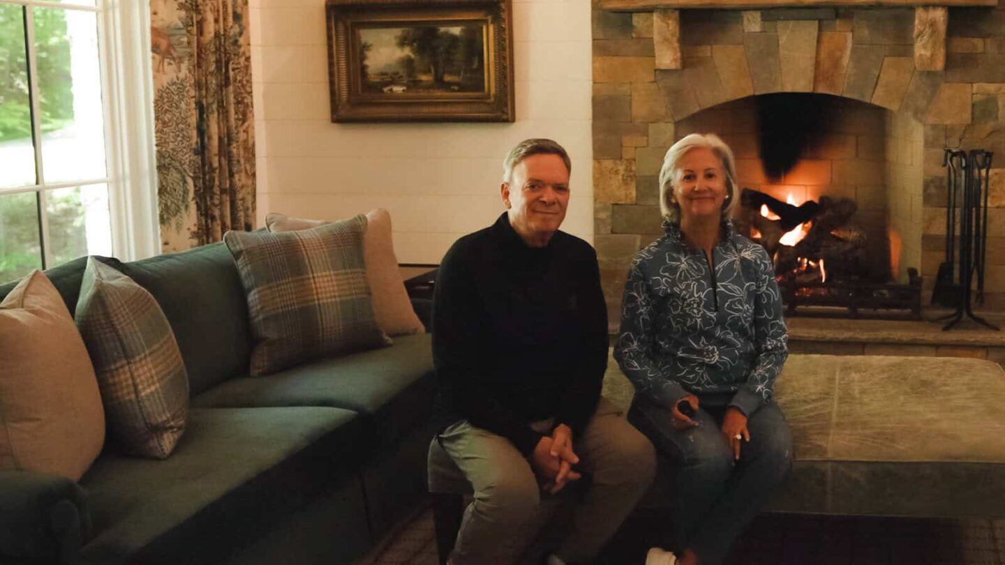 Happy homeowners relaxing by a stone fireplace in their custom Natural Element Home